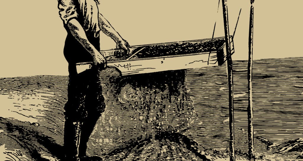 A farmer using a wooden soil sifter, ensuring the soil is fine and debris-free for planting.